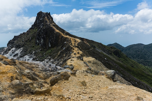 Bellissimo scatto di una montagna sotto un cielo nuvoloso blu