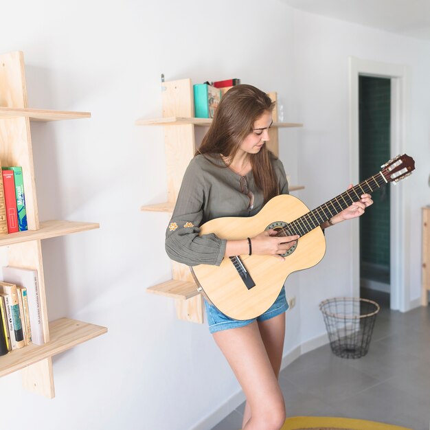 Bello adolescente che gioca chitarra a casa