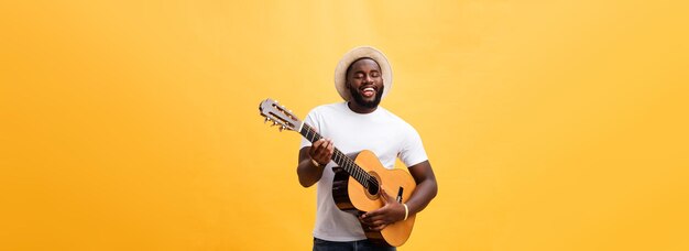 Bello chitarrista afroamericano in stile retrò che suona la chitarra acustica isolato su sfondo giallo