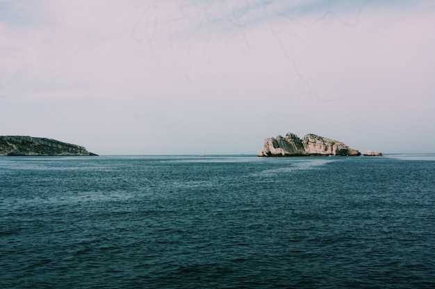 Bello colpo del mare con le rocce e le scogliere sotto un cielo nuvoloso