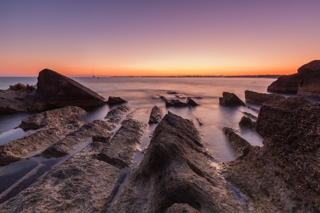 Bello colpo del mare con le scogliere e le rocce durante il tramonto