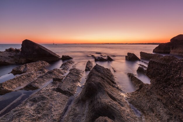Bello colpo del mare con le scogliere e le rocce durante il tramonto