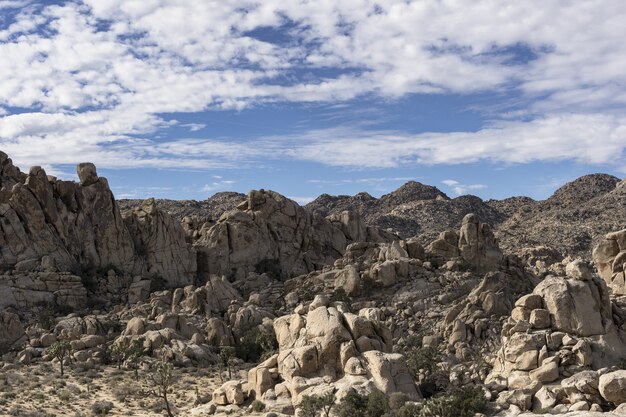 Bello colpo delle colline e delle montagne rocciose sotto un cielo nuvoloso blu di giorno