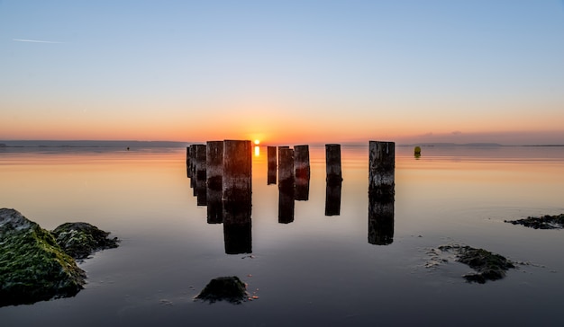 Bello colpo delle colonne consumate del pilastro su uno specchio d'acqua durante il tramonto. Perfetto per uno sfondo