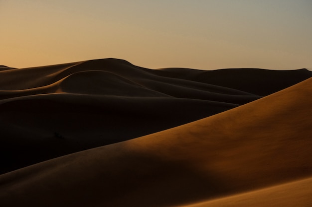 Bello colpo delle dune di sabbia con il chiaro cielo