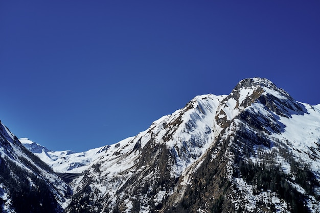 Bello colpo di angolo basso di una montagna con neve che copre il picco e il cielo nei precedenti