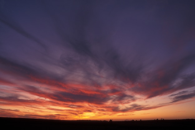 Bello colpo di un cielo porpora ed arancio con le nuvole al tramonto a Guimaras, Filippine