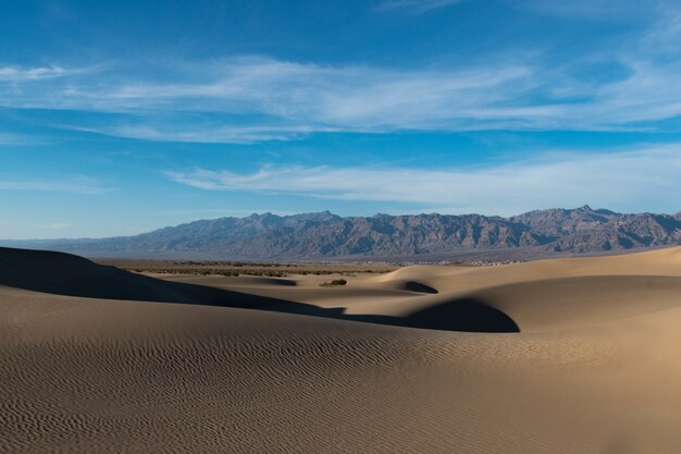 Bello colpo di un deserto con le tracce sulla sabbia e le colline rocciose sotto il cielo calmo