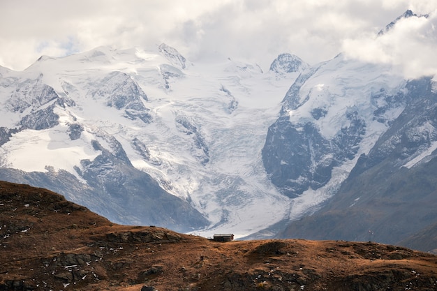 Bello colpo di una casa sul bordo della scogliera con montagne innevate