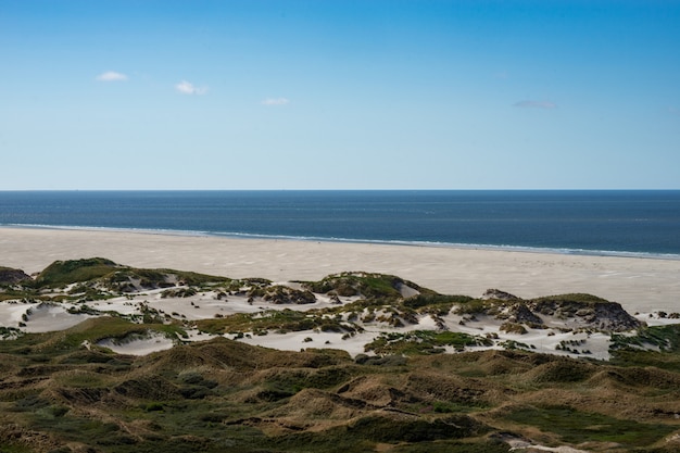 Bello colpo di una spiaggia vuota pacifica un giorno soleggiato con il mare calmo stupefacente e le nuvole chiare