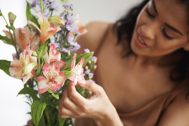 Bello fiorista femminile africano che fa mazzo di fiori. Focus su alstroemerias.