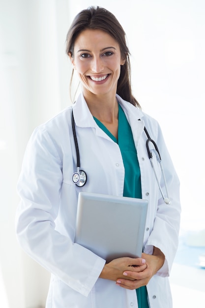 Bello giovane medico femminile che esamina macchina fotografica nell&#39;ufficio.