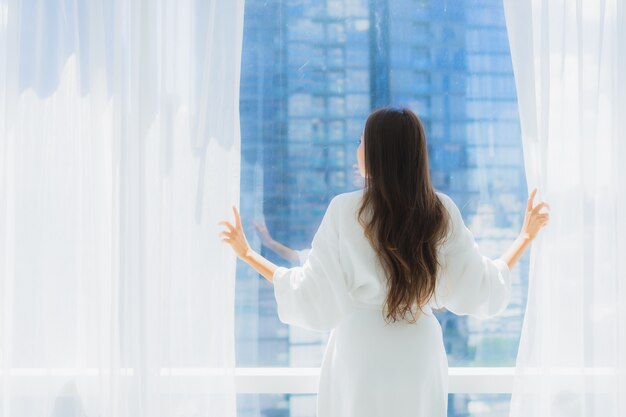 Bello giovane sguardo asiatico della donna del ritratto fuori della finestra per la vista