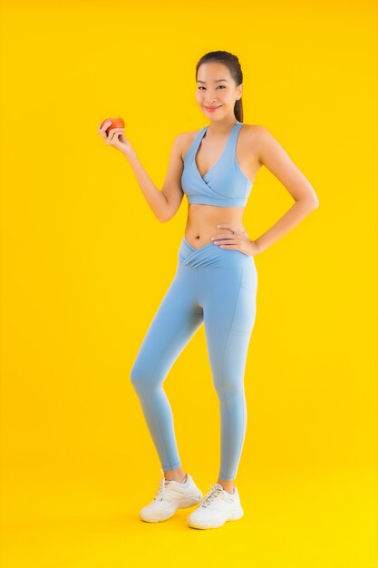 Bello giovane sportwear asiatico di usura di donna del ritratto pronto per l'esercizio su giallo