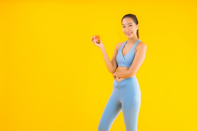 Bello giovane sportwear asiatico di usura di donna del ritratto pronto per l'esercizio su giallo