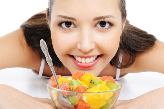 Bello giovane volto femminile sotto la ciotola con insalata di frutta