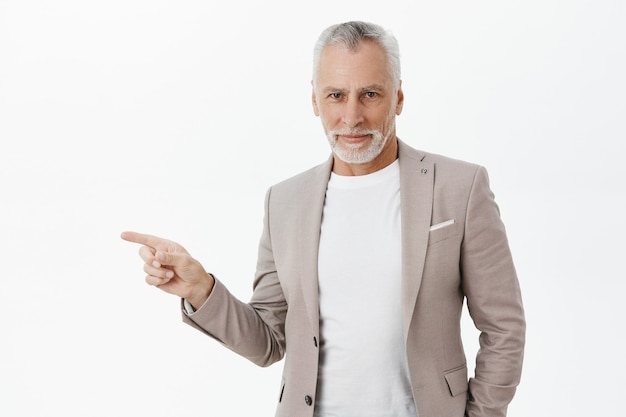 Bello imprenditore con i capelli grigi che punta il dito a sinistra