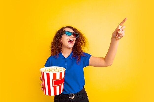 Bello modello riccio femminile in camicia che indica con popcorn