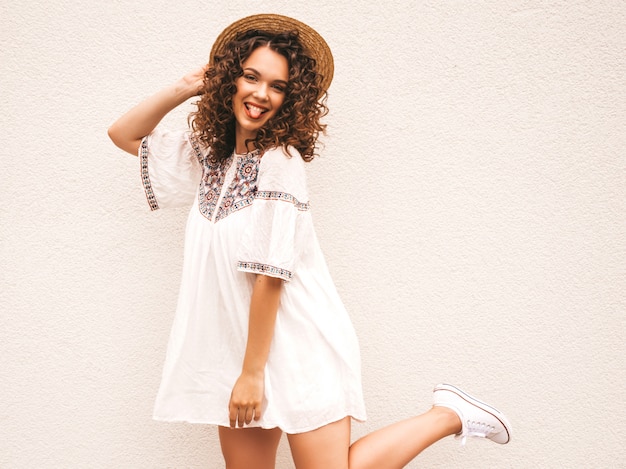 Bello modello sorridente con l'acconciatura di riccioli afro vestito in abito bianco hipster estate.