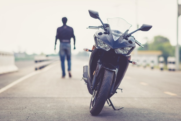 Bello motociclista con il casco nelle mani della moto