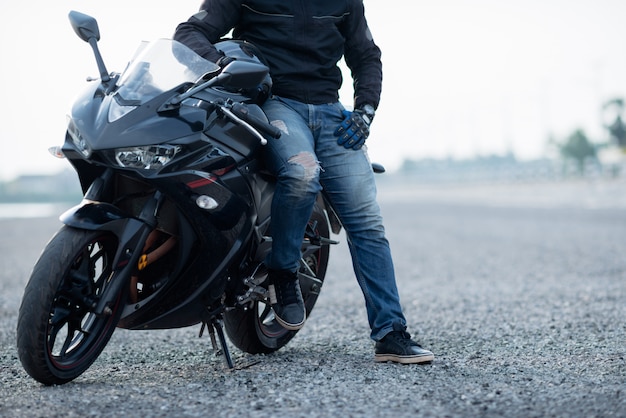 Bello motociclista con il casco nelle mani della moto