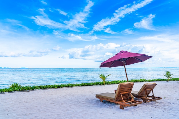 Bello paesaggio dell'oceano del mare della spiaggia con la piattaforma e l'ombrello vuoti della palma quasi del cocco con la nuvola e il cielo blu bianchi