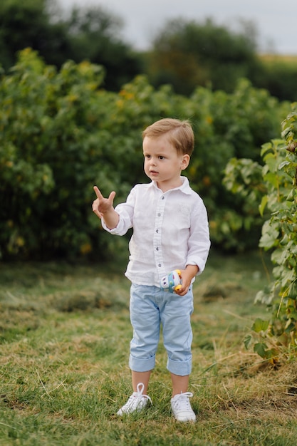 Bello ragazzo che gioca con le bolle il giorno soleggiato nel giardino.