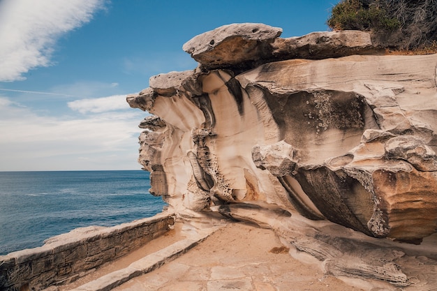 Bello scatto di una ripida scogliera rocciosa vicino al mare con un cielo blu