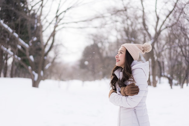Bello sorridere asiatico della giovane donna felice per il viaggio nella stagione invernale della neve