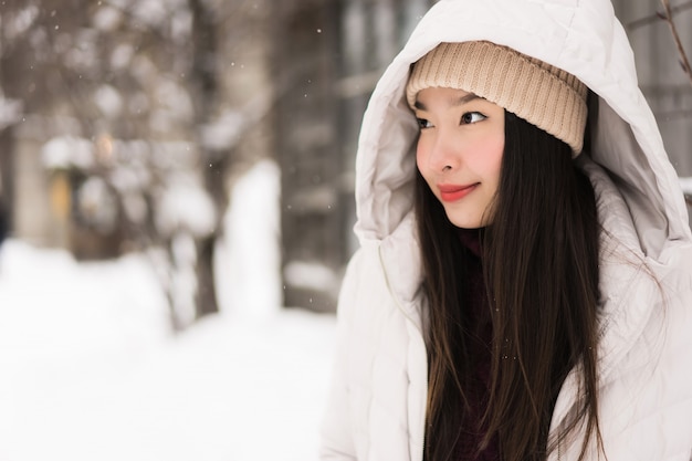 Bello sorridere asiatico della giovane donna felice per il viaggio nella stagione invernale della neve