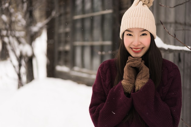 Bello sorridere asiatico della giovane donna felice per il viaggio nella stagione invernale della neve