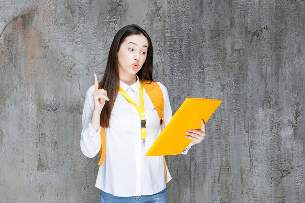 Bello studente in camicia bianca che tiene libro e indica. Foto di alta qualità