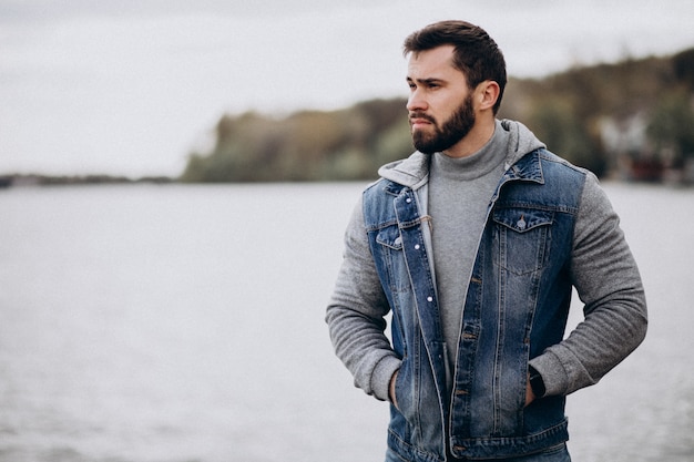 Bello uomo barbuto vicino al fiume nel parco