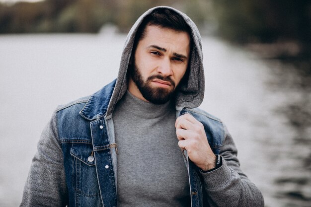 Bello uomo barbuto vicino al fiume nel parco