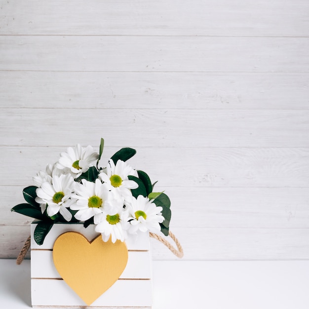 Bello vaso di fiore bianco decorativo con forma del cuore contro il contesto di legno