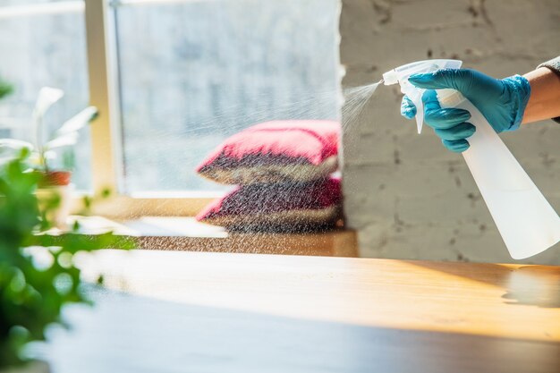 Beni essenziali durante l'epidemia - prevenzione e protezione della diffusione del coronavirus COVID-19. Guanti a mano disinfettando le superfici con disinfettante a casa. Pulizia contro il virus della polmonite.