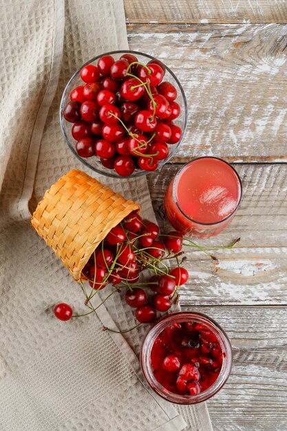 Bevanda ciliegia con ciliegie, marmellata in una brocca sul telo da cucina in legno