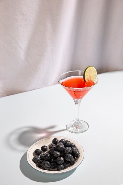 Bevanda del cocktail con le bacche blu sul piatto contro fondo bianco