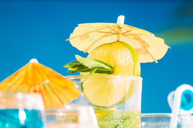 Bevanda leggera con lime a fette e menta in vetro decorato a ombrello
