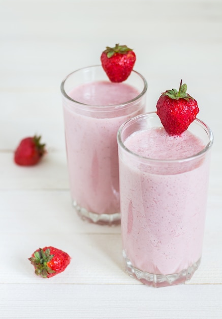 Bevanda sana della prima colazione del frullato della fragola in vetro su legno bianco. Foto verticale di stile di vita sano cibo delizioso