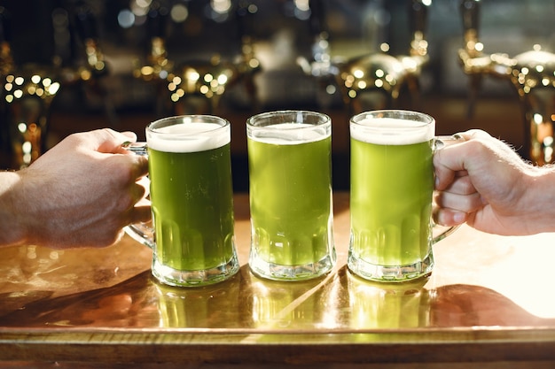 Bevanda verde in vetro. Bicchiere in mano d'uomo. Birra al bar.