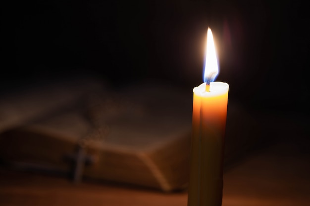 Bibbia e candela su una vecchia tavola di legno di quercia.