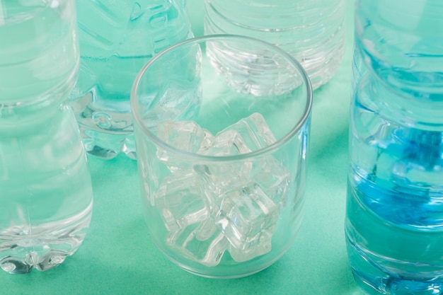 Bicchiere d'acqua e bottiglie di plastica ad alta vista