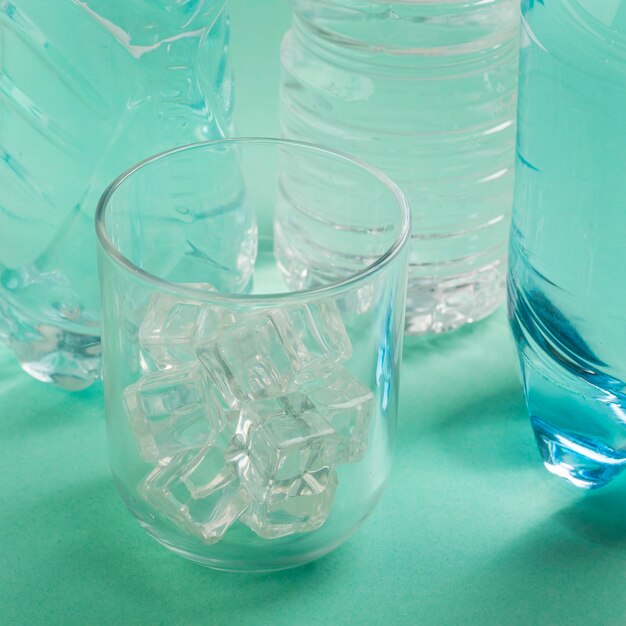 Bicchiere d'acqua e bottiglie di plastica