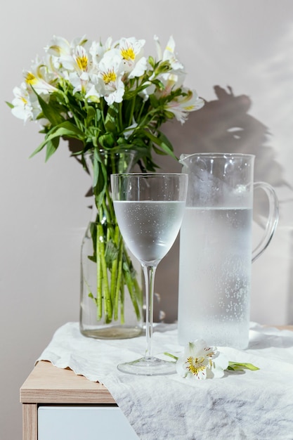 Bicchiere d'acqua e vaso con fiori