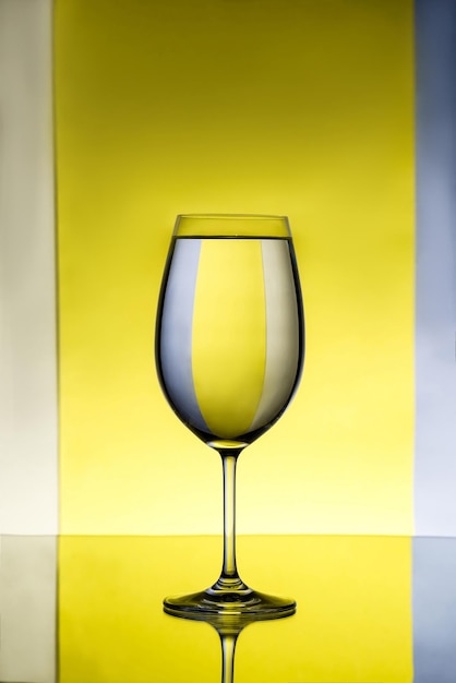 Bicchiere da vino con acqua su sfondo grigio e giallo
