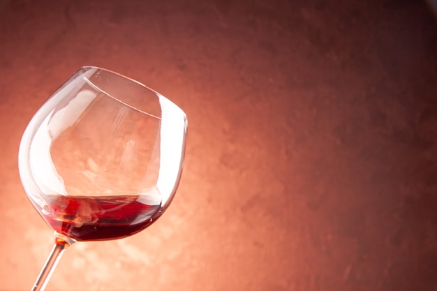 Bicchiere da vino vista frontale con poco vino all'interno su bevanda alcolica di Natale champagne di colore scuro