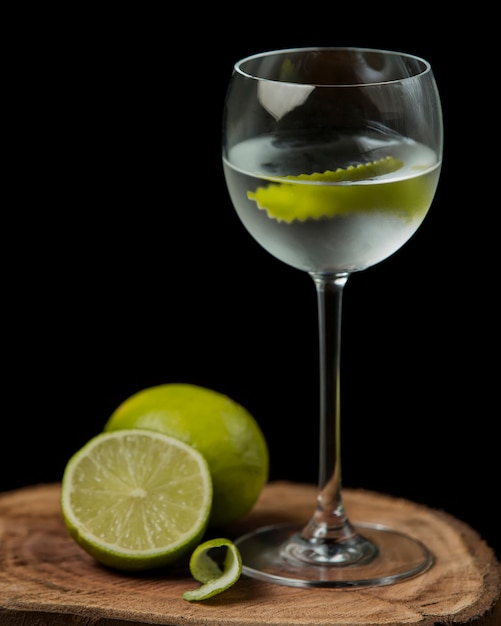 Bicchiere di acqua di calce con scorza di lime su tavola di legno