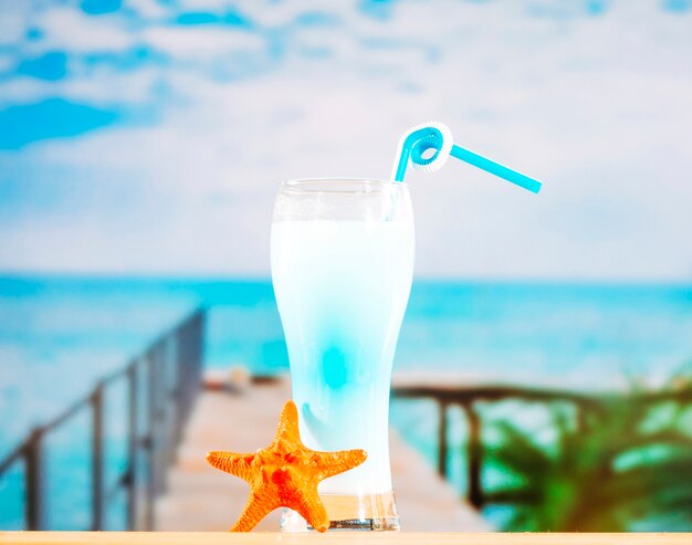 Bicchiere di bevanda blu congelato con paglia e stelle marine