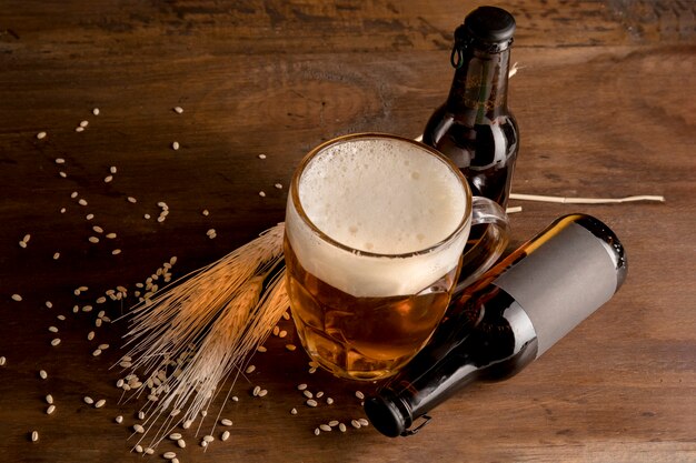 Bicchiere di birra con bottiglie marroni di birra sul tavolo di legno